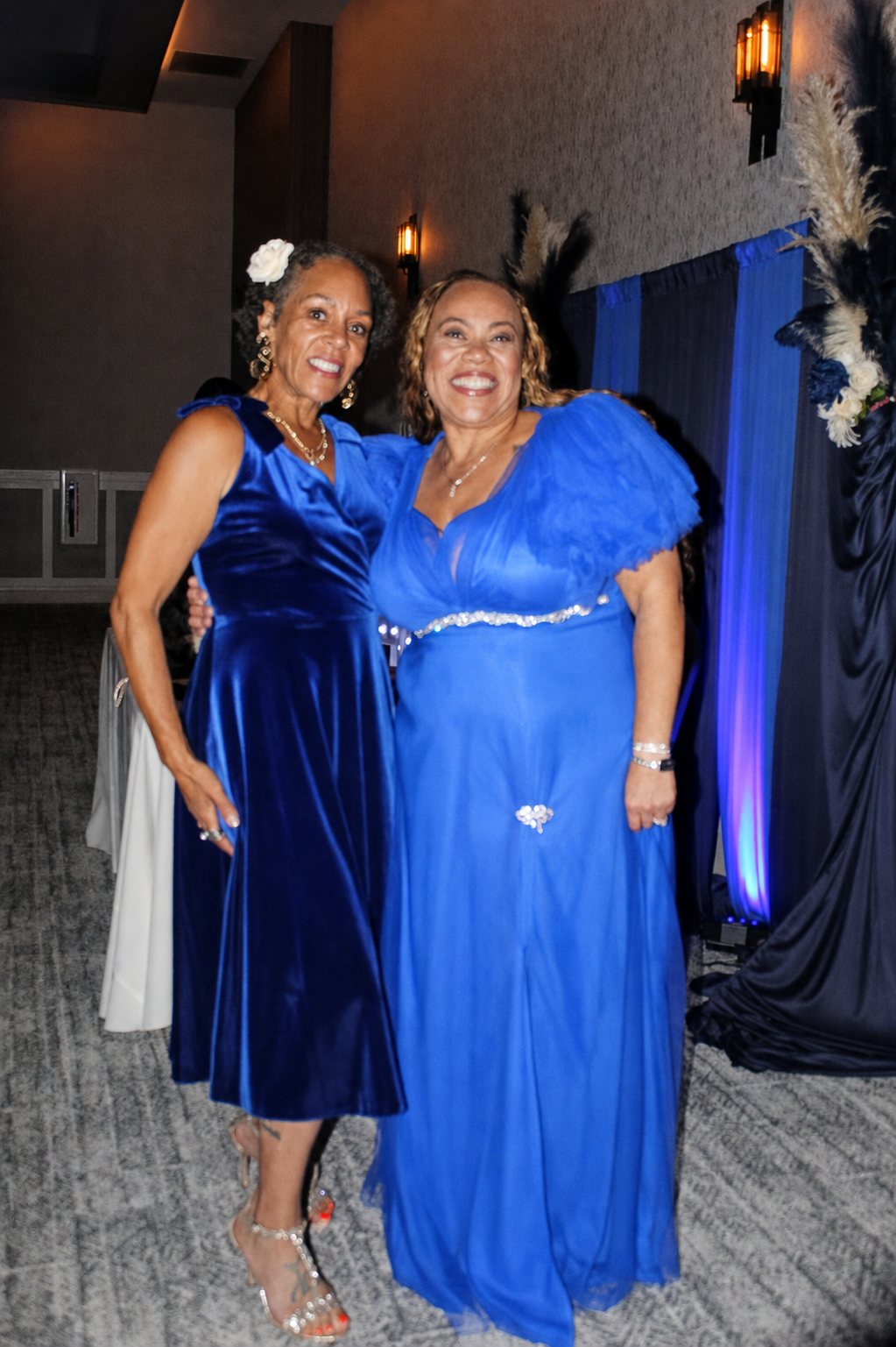 Two women in blue dresses standing together at the birthday celebration